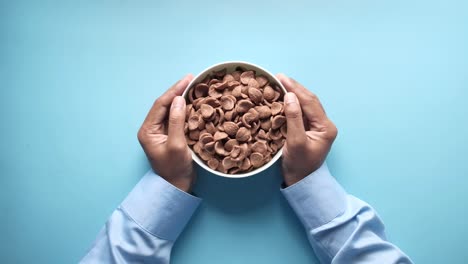 hands holding a bowl of chocolate cereal
