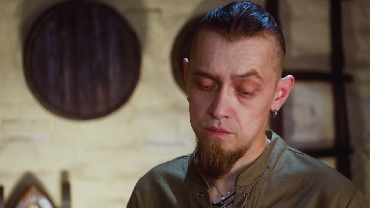 hombre incierto en un restaurante medieval de primer plano. huésped con barba de cabra oscura piensa en una pregunta difícil en el viejo hotel. fantasía de la edad oscura y juego de rol