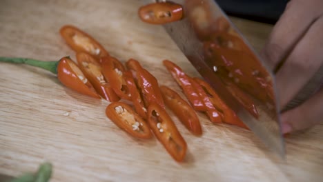 cortar un pimiento rojo en rodajas con un cuchillo en una tabla de cortar de madera - cerrar