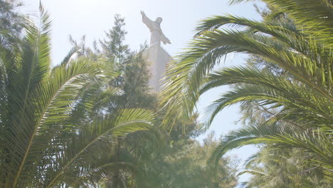 pan to christ the king statue between palms in aflama next to lisbon