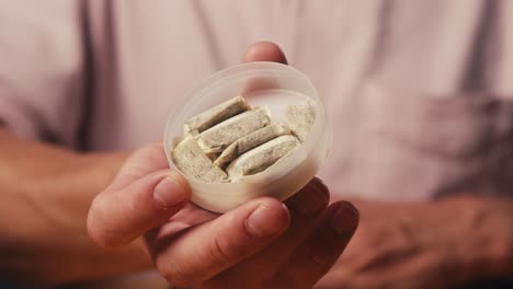 snus nicotine tobacco close up, pack of tobacco for gum. unhealthy addiction. man opening box with snus and taking one.