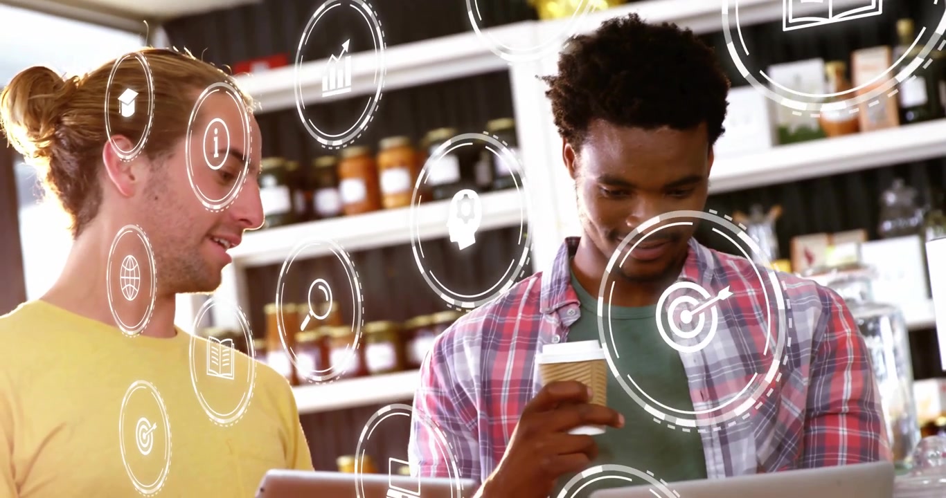 Two colleagues using tablet and laptop in retail cafe, displaying floating interface icons