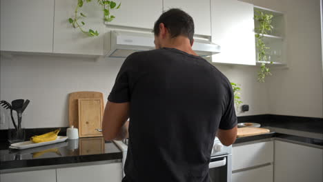 movimiento lento de un latino mexicano hombre en forma cocinando mientras escucha una canción bailando y cantando teniendo un gran momento a solas