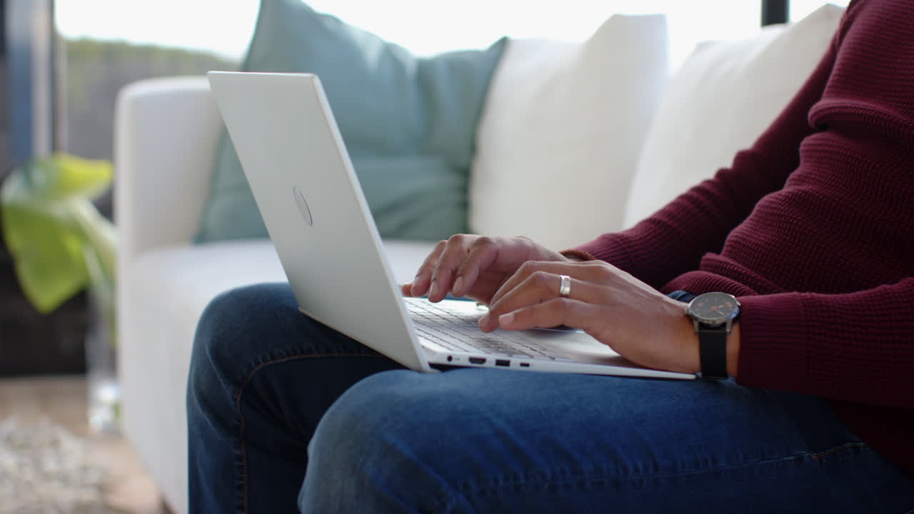 Typing on laptop, person sitting on couch working from home