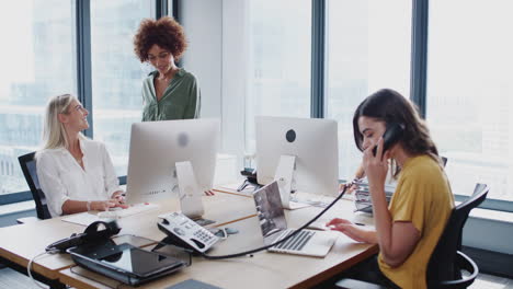 millennial black woman walking around an office talking to her female creative colleagues, arc shot