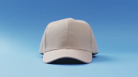 Video-of-beige-baseball-cap-and-copy-space-on-blue-background