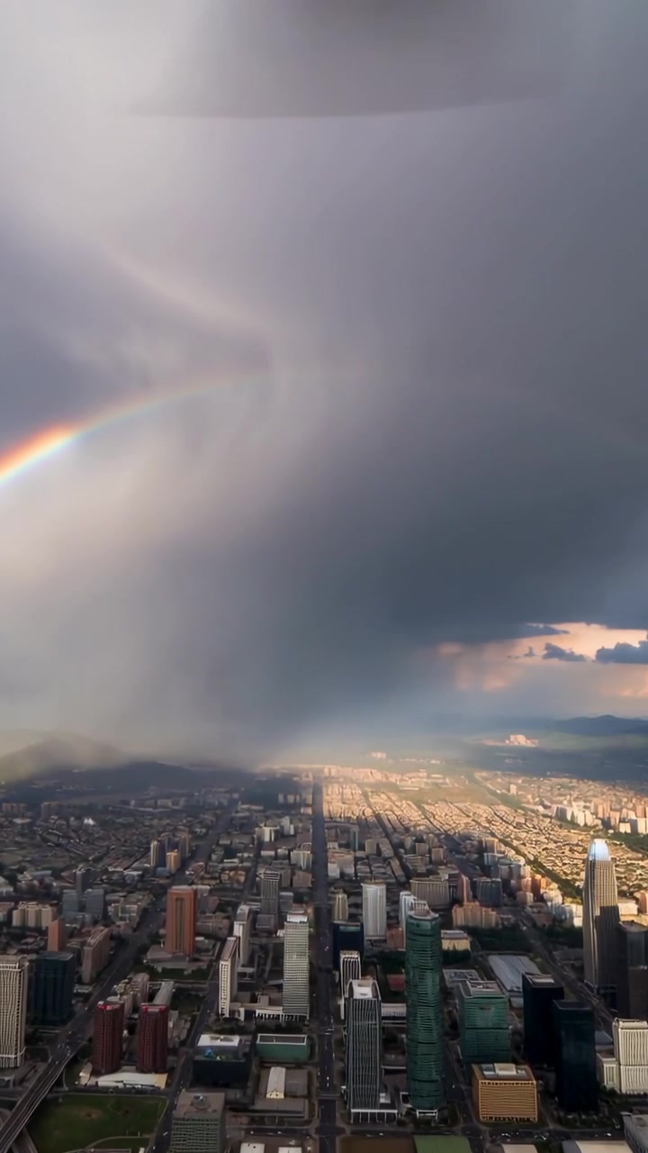 Vertical video: Showing sun piercing clouds, downtown avenue rain shaft growing and rainbow fading