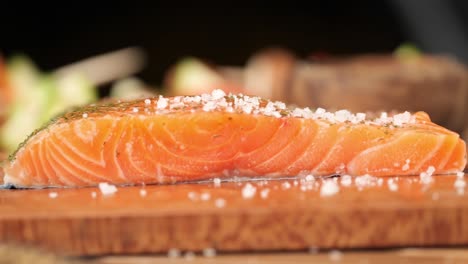 la sal se rocía sobre un salmón crudo en una tabla de madera de cerca