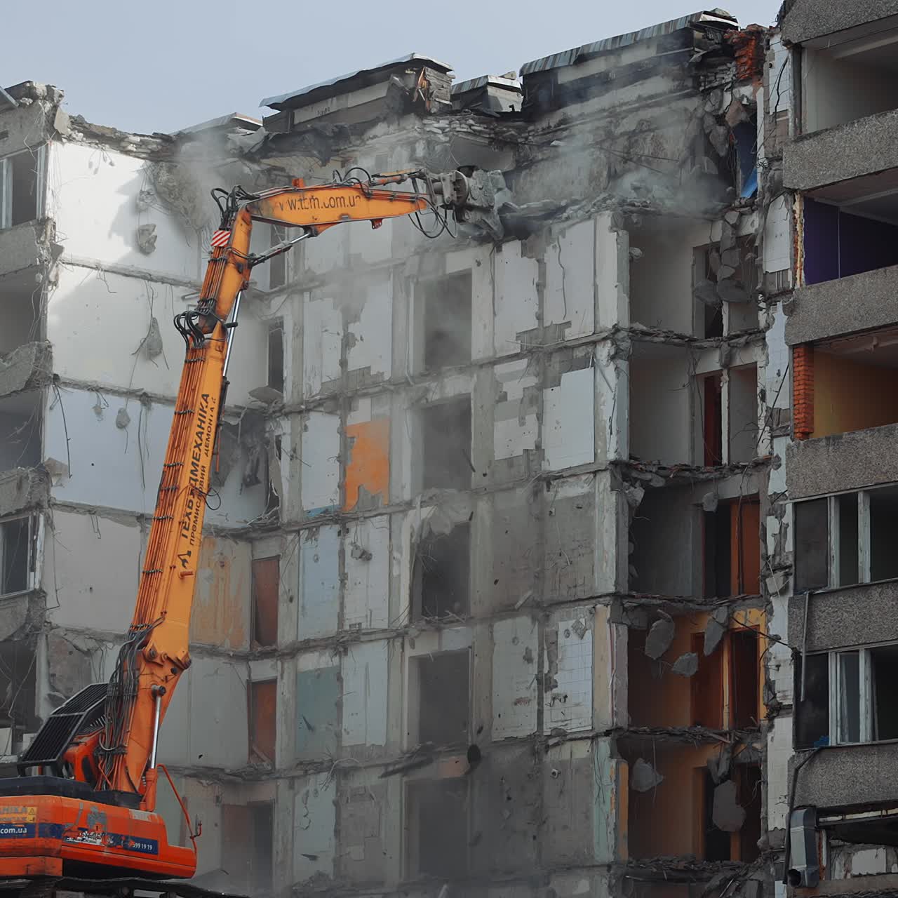 Collapse of the ruined roofs of an old house. Excavator grabber tears off the pieces of the roof. Blue sky at the backdrop