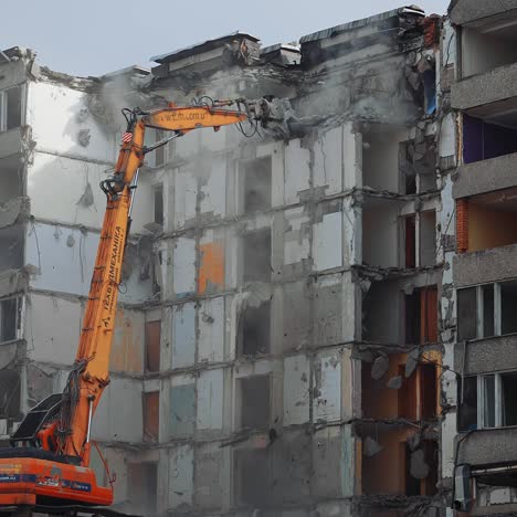 collapse of the ruined roofs of an old house. excavator grabber tears off the pieces of the roof. blue sky at the backdrop
