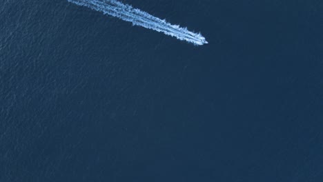 high aerial view of a speed boat cruising across the deep blue waters of the ocean