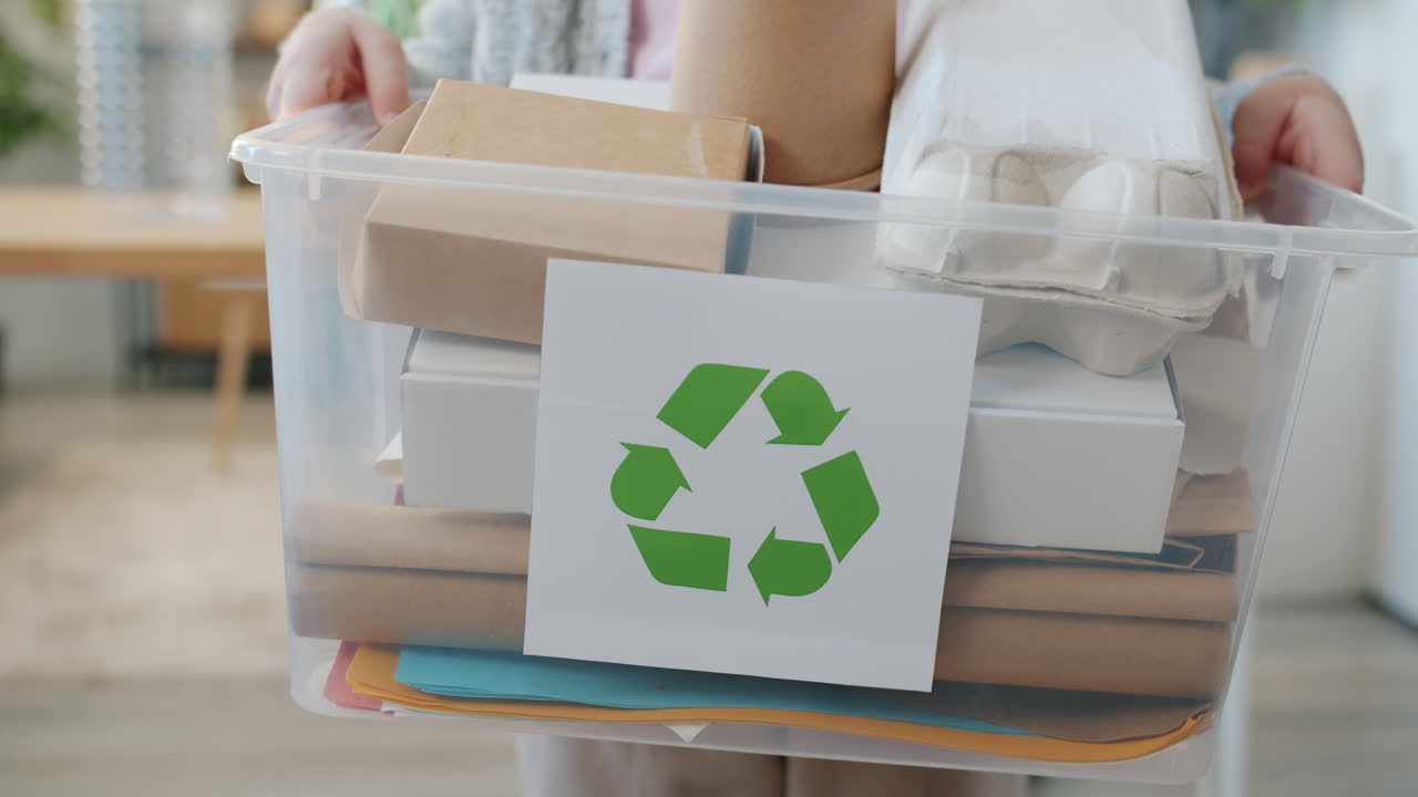 Person Holding a Recycling Bin Filled with Various Recyclable Materials