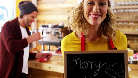 portrait of waitress showing slate with merry x-mas sign