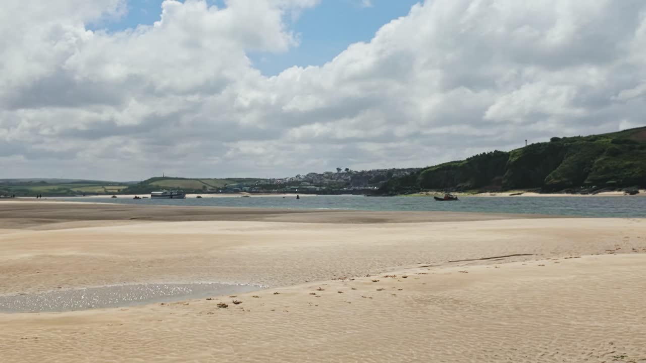 Right to left pan of view from Daymer Bay towards Padstow at low tide, sand in foreground