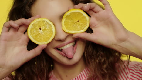 Chica-Juguetona-Divirtiéndose-Con-Rodajas-De-Limón-Sobre-Fondo-Amarillo.-Mujer-Alegre