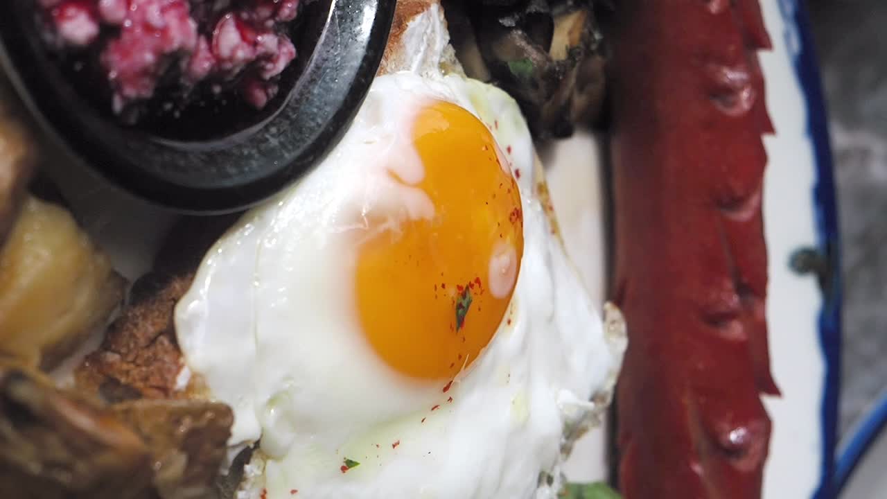 Aamiaisateria paistetulla kananmunalla, avokadolla, makkaralla ja perunoilla