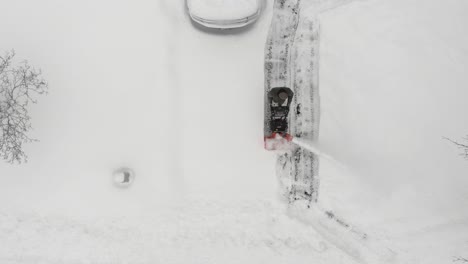 adult man clears driveway covered with thick snow using snowblower at wintertime