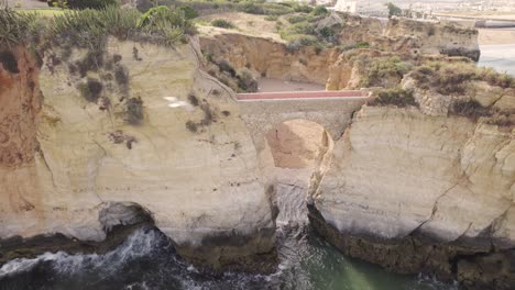 Toma-Aérea-De-La-Ruta-Del-Acantilado-Costero-De-Ponta-Da-Piedade-Y-El-Puente-En-Portugal