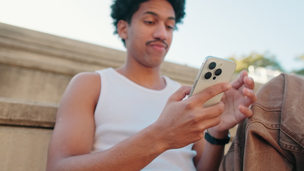 Thoughtful Young Man Browsing Smartphone Outdoors