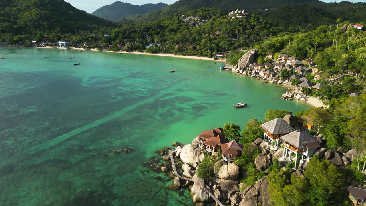 Koh Tao south east Asia tropical paradise with sand beach and pristine ocean clear water sea, drone revealing bay with beach resort luxury accommodation above the rocky cliff