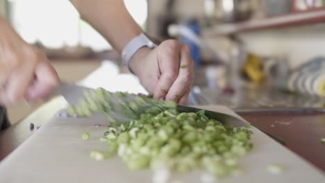 un chef cortando verduras con un cuchillo de chef afilado en una tabla de cortar