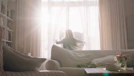 happy little girl opening curtains looking out window at beautiful new day with bright sunlight playful child feeling positive about future