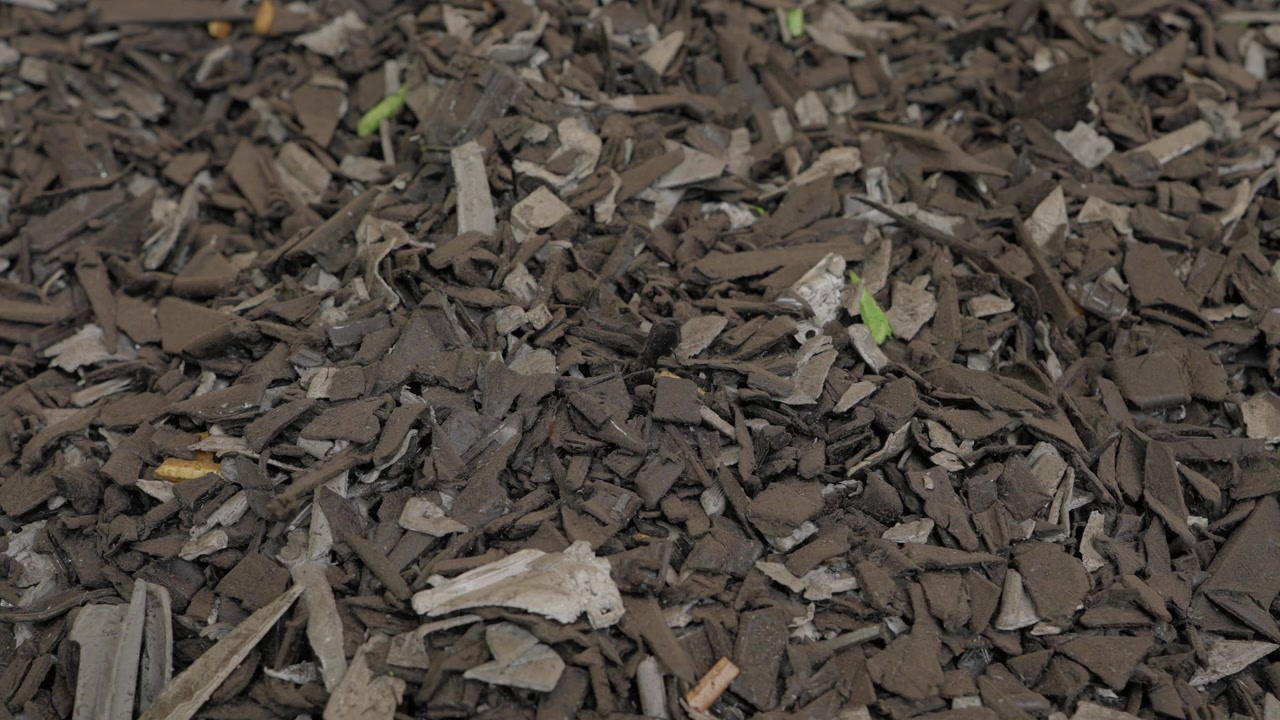Closeup of ground recycled plastic flakes and shredded fragments at factory