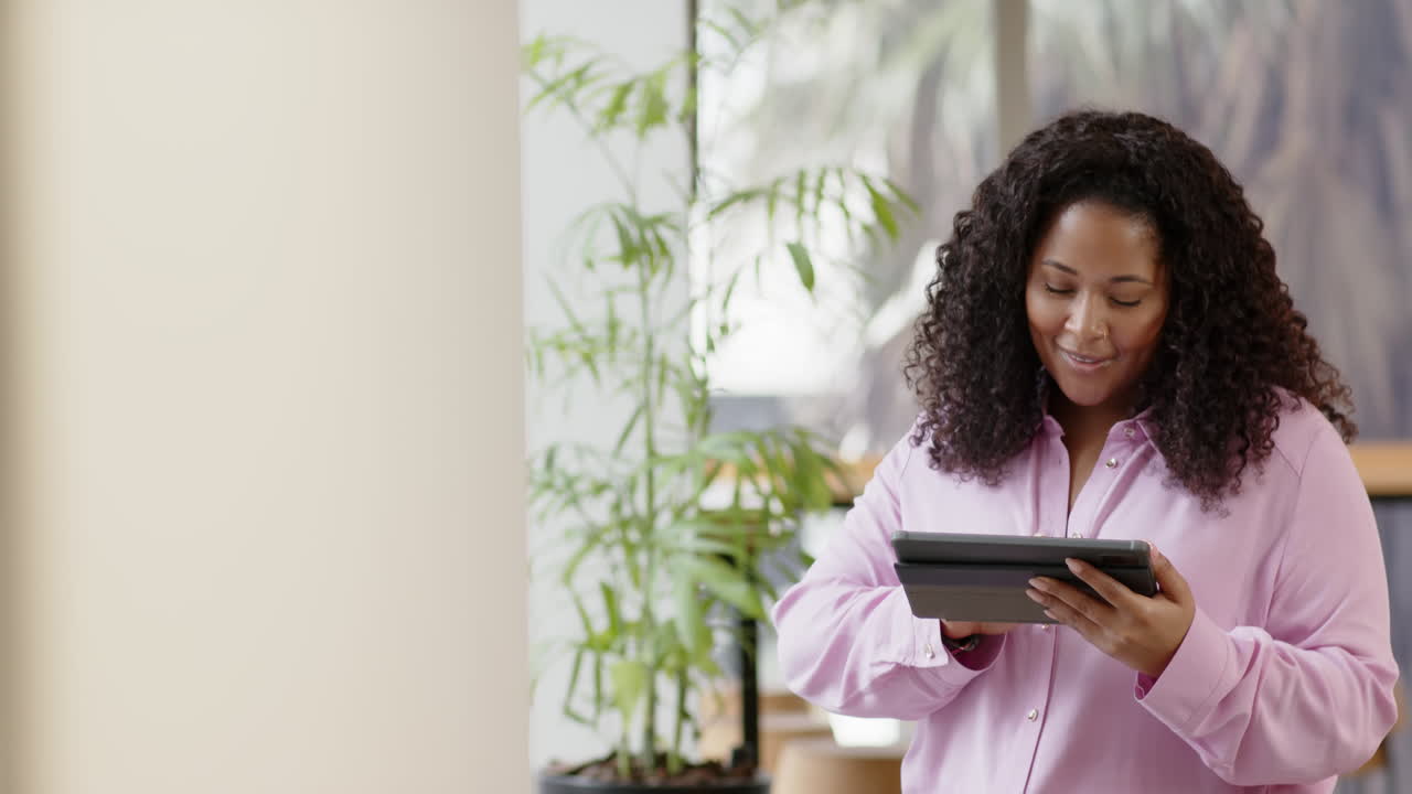 Casual biracial businesswoman using tablet in office, slow motion with copy space