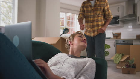 couple unpacking boxes after moving into new home together making video call on  laptop