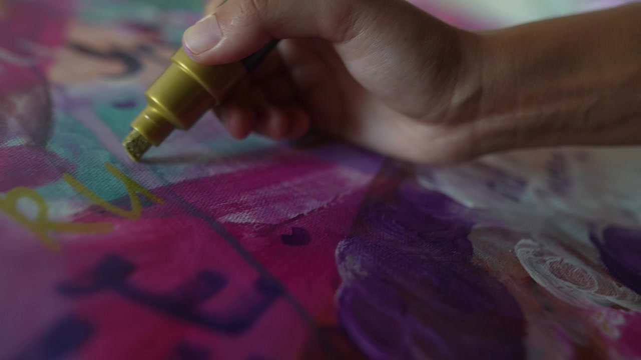 Artista che dipinge arte astratta con pennarello dorato su tela
