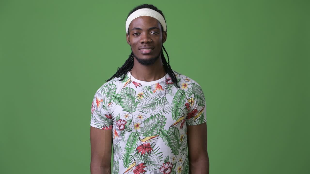 joven hombre africano guapo con dreadlocks contra un fondo verde
