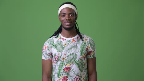 young handsome african man with dreadlocks against green background