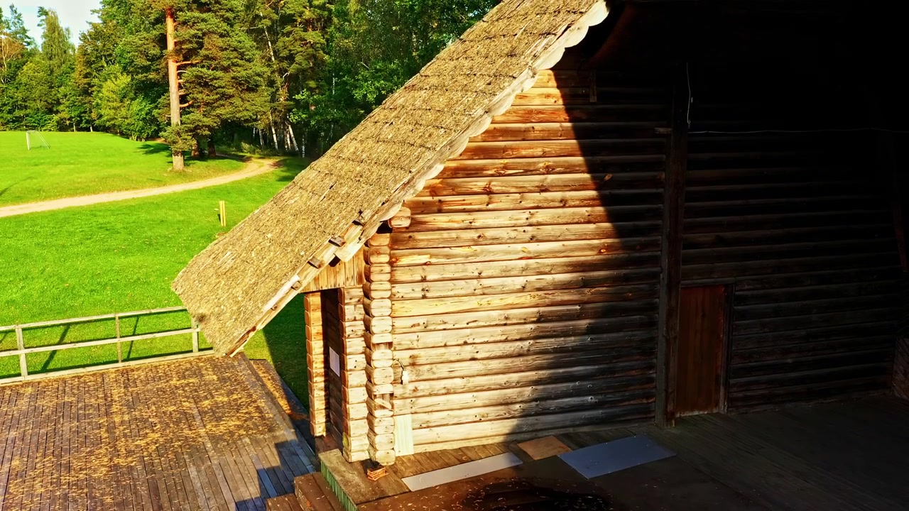Tradizionale baita in legno con un patio in legno circondata da un prato verde.