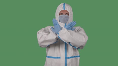 retrato de un hombre con un traje de protección y una máscara médica cruza los brazos mostrando una parada y ningún gesto, y luego un pulgar hacia arriba, un pulgado hacia abajo y ok. pantalla verde, tecla de croma. cámara lenta.