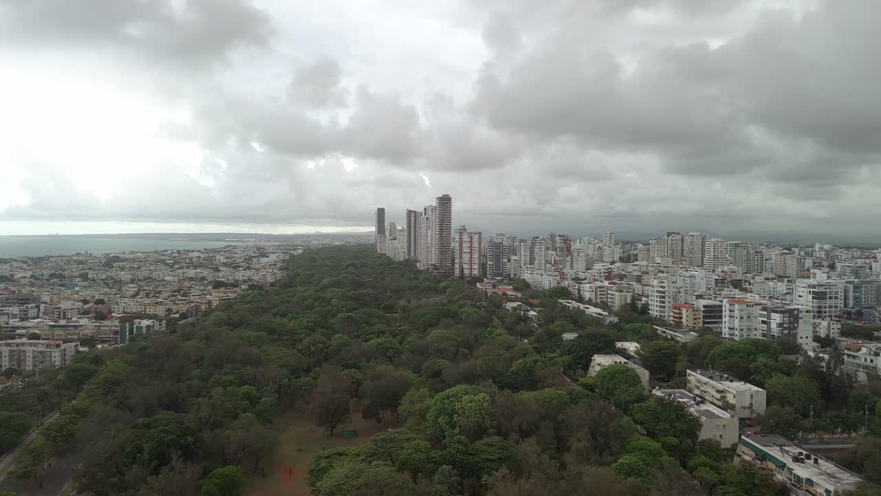 Vista aerea da drone del Parque Mirador Sur che costeggia la città di Santo Domingo. Il verdeggiante parco urbano contrasta con lo skyline sotto un cielo tempestoso, Repubblica Dominicana