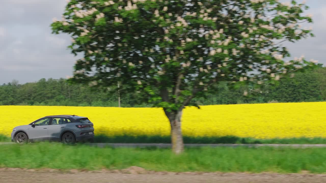 회색 suv가 농장  ⁇ 을 가로질러 운전하고, 회색 구름이 가득한 하늘, 트래킹 팬