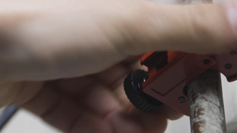 extreme closeup of a man's hands cutting a copper water pipe with a pipecutter