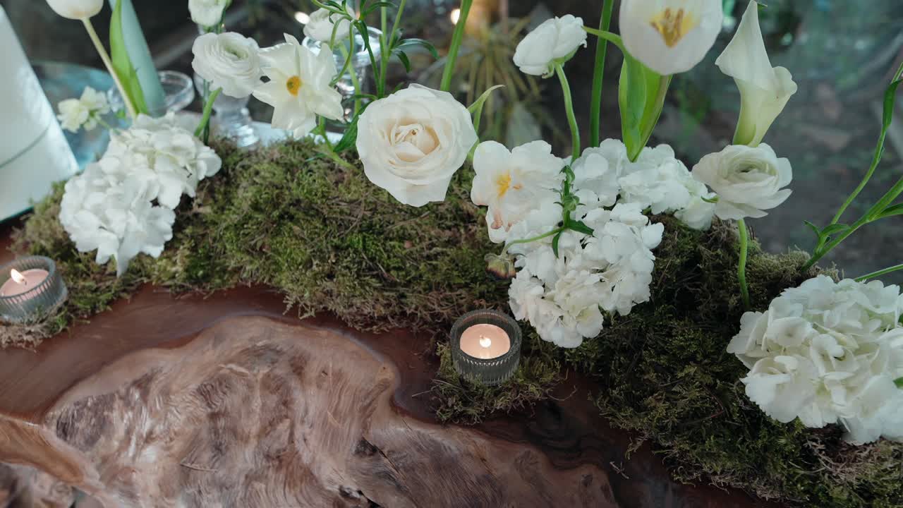 elegant white flowers and moss centerpiece with candles on natural wood surface