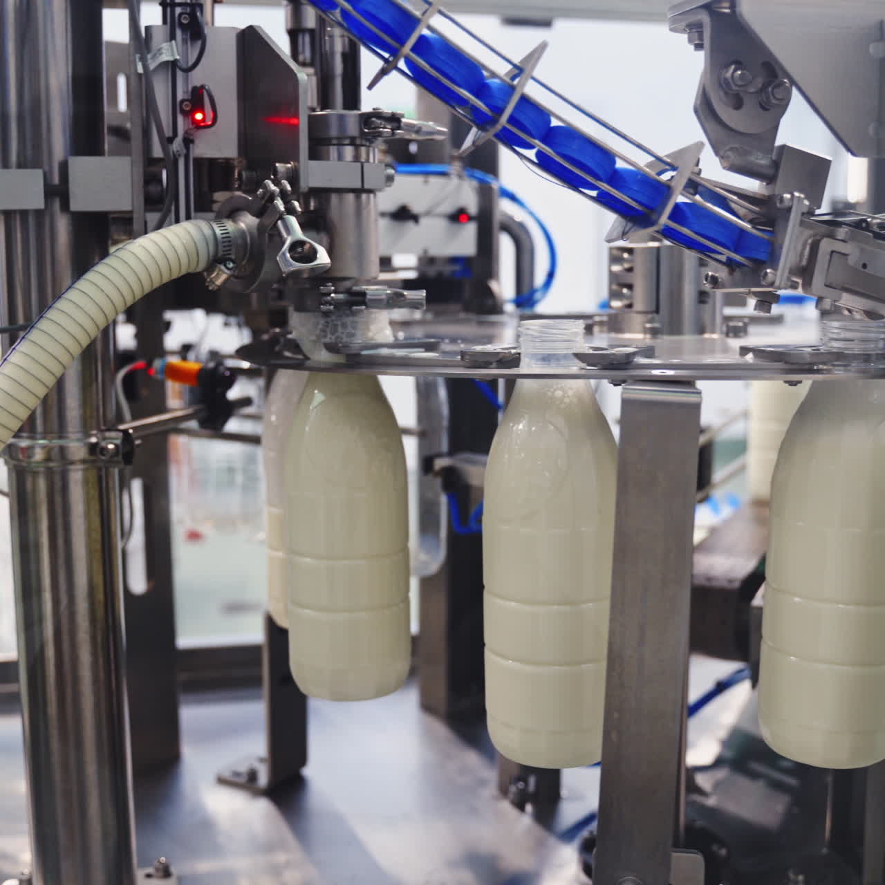 Robotic process for filling bottles with milk in a factory. Milk is pouring into plastic bottles by a special automatic equipment in a modern dairy plant.