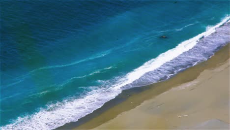 Toma-Aérea-De-Agua-Turquesa-Y-Olas-Rodando-En-Una-Playa-De-Arena-Blanca,-Playa-De-Ward,-Nueva-Zelanda---Toma-Estable