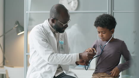 little african american boy playing with stethoscope at doctors office