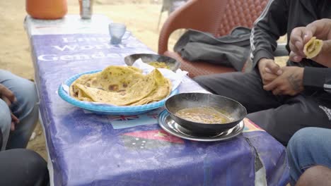 people relish a delightful breakfast at a charming local dhaba, which features warm, crispy parathas, flavorful omelets, tea, and refreshing raita.