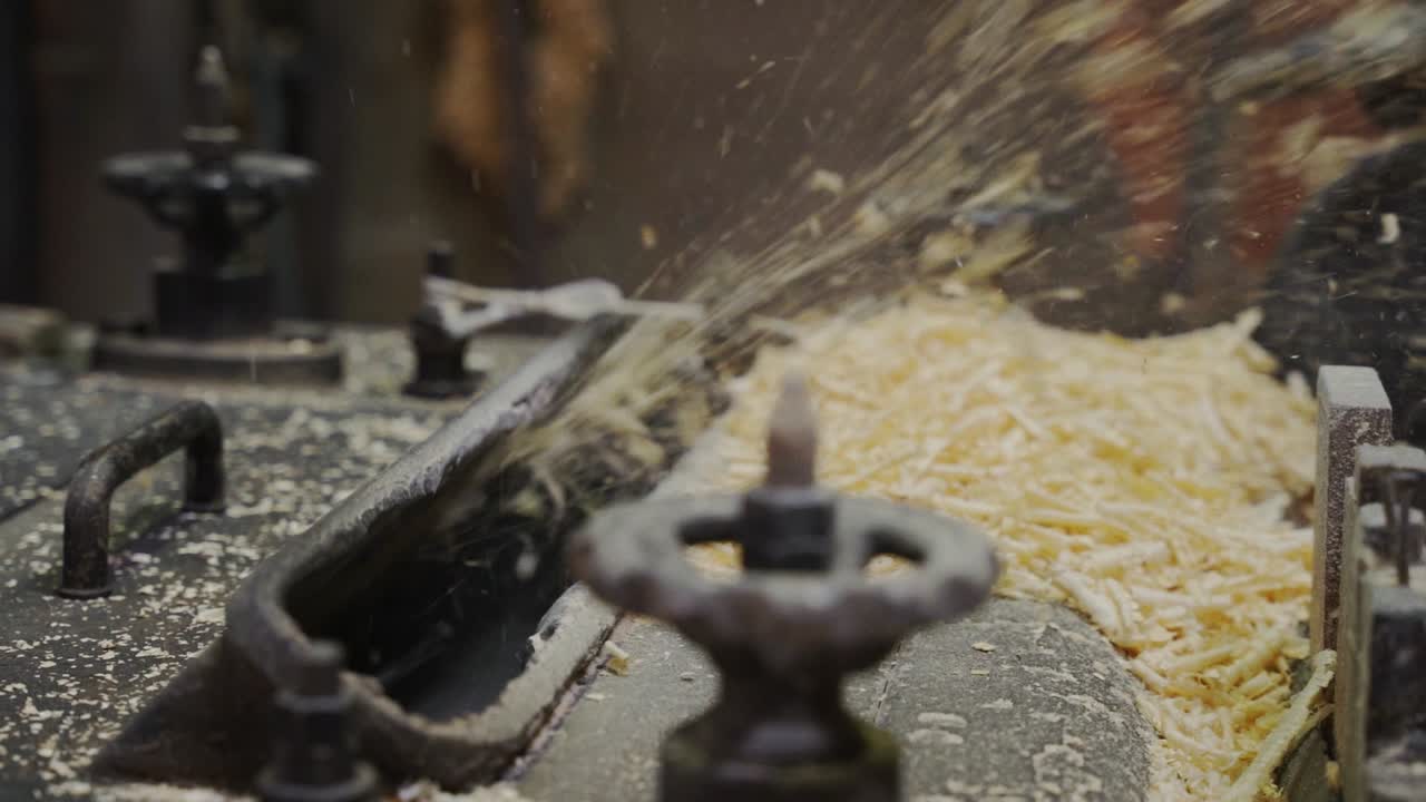 Máquina triturando tábua de madeira, produzindo serragem.