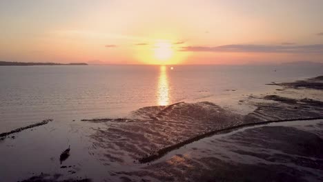 aerial view of beautiful ocean sunset in thailand - camera tracking above water at low tide