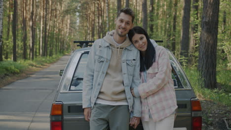 couple posing beside a vintage car in a forest