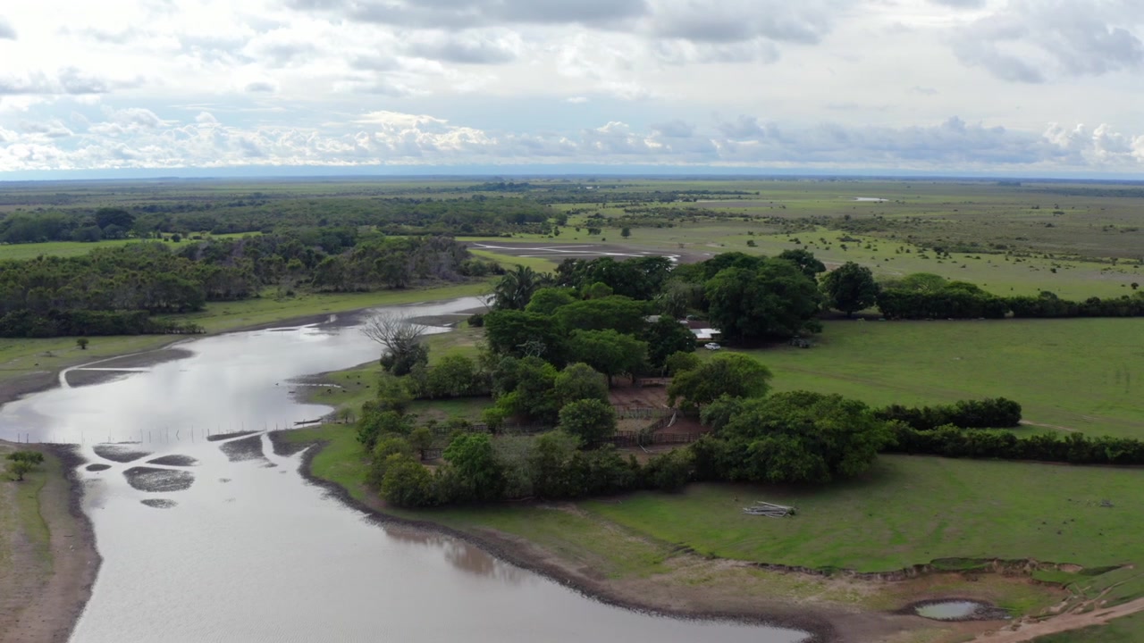Fiume serpeggiante che attraversa la savana verde, alberi sparsi e piccoli stagni nella regione dei Llanos Orientales della Colombia, ripresa aerea in allontanamento