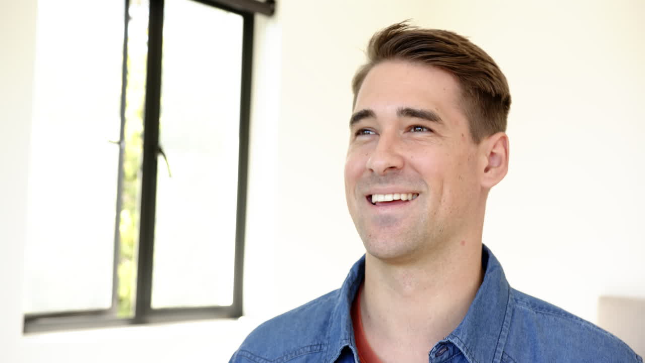 Smiling man in casual denim shirt looking away, feeling happy and relaxed, at home, copy space
