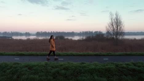 paralex shot, girl walking down on a dam, at early morning with the river in the background