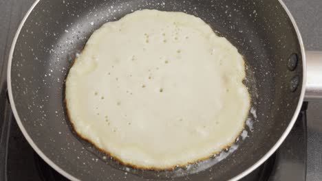 cocinando un panqueque con aceite en la sartén