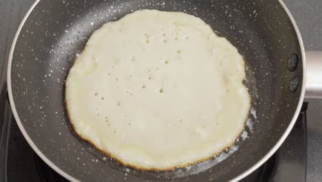 cooking a pancake with oil in frying pan